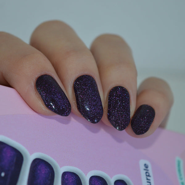 Hand wearing Cat Eye Purple Super Jellies next to the gel nail wrap sheet