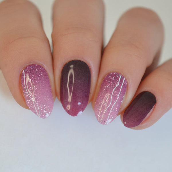 Nails with a gradient design of purple and brown on a neutral background