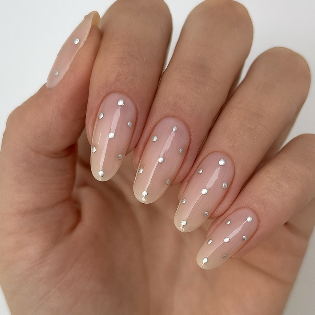 Hand with clear nail polish and small decorative dots on a white background

