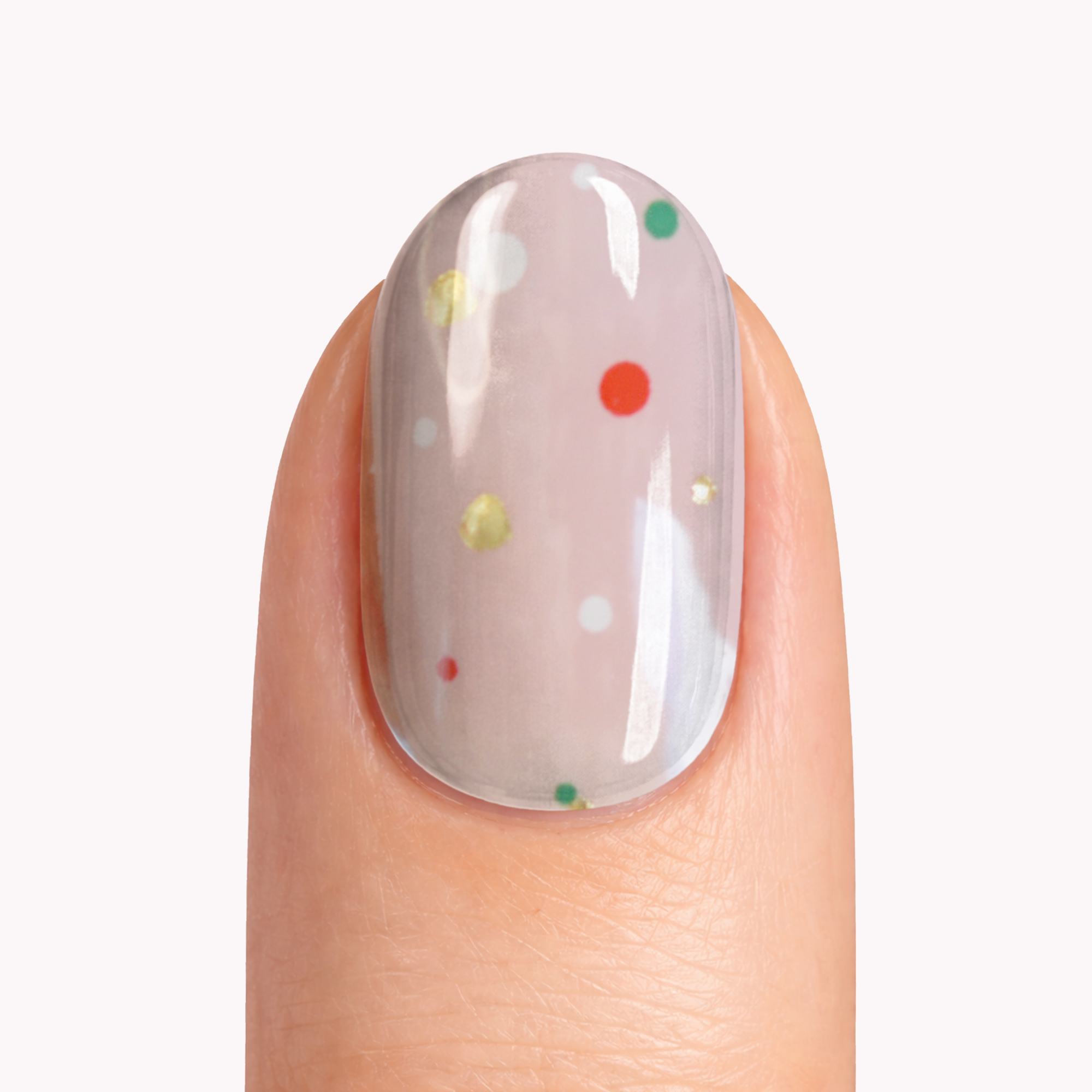 Close-up of a single nail wearing Freckles Super Jellies, sheer pink gel nails with red, green, white and gold dots