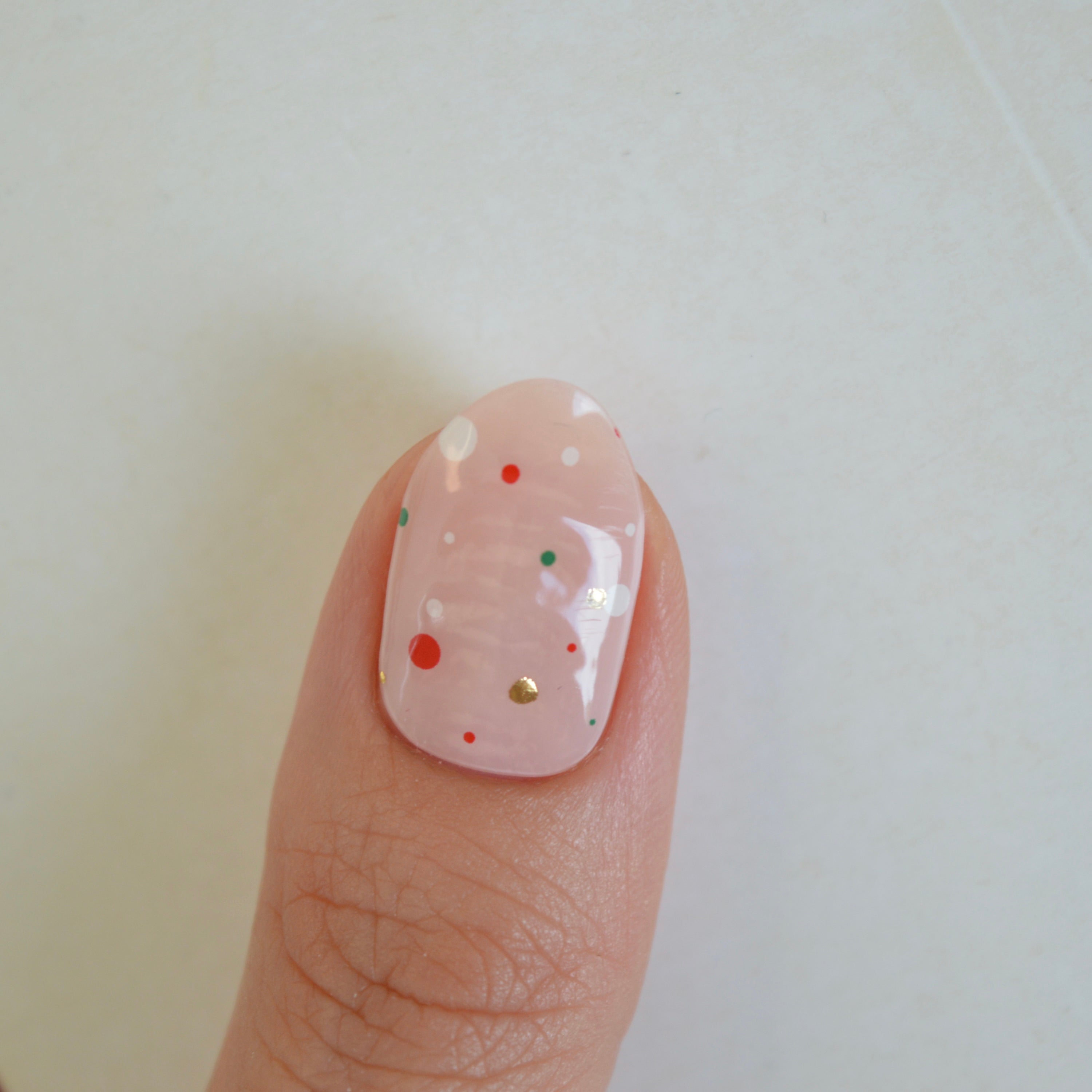 Freckles Super Jellies, sheer pink gel nails with red, green, white and gold dots