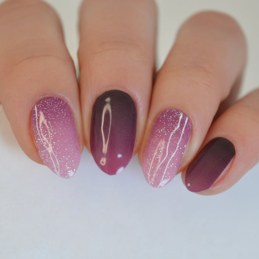 Nails with a gradient design of purple and brown on a neutral background